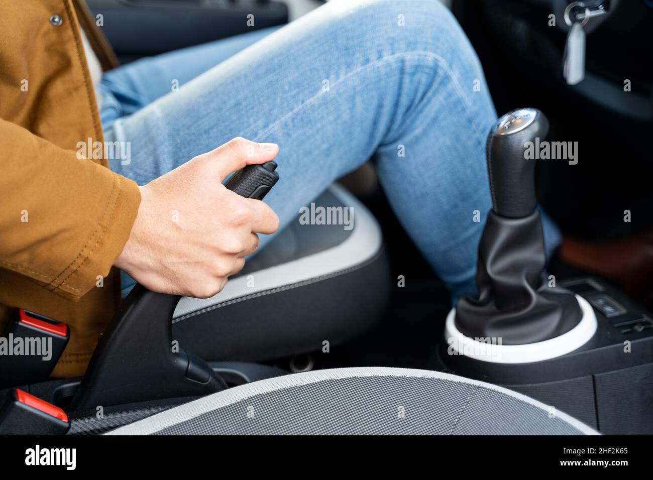 Man moves handbreak sitting on driver's seat in car with manual gear