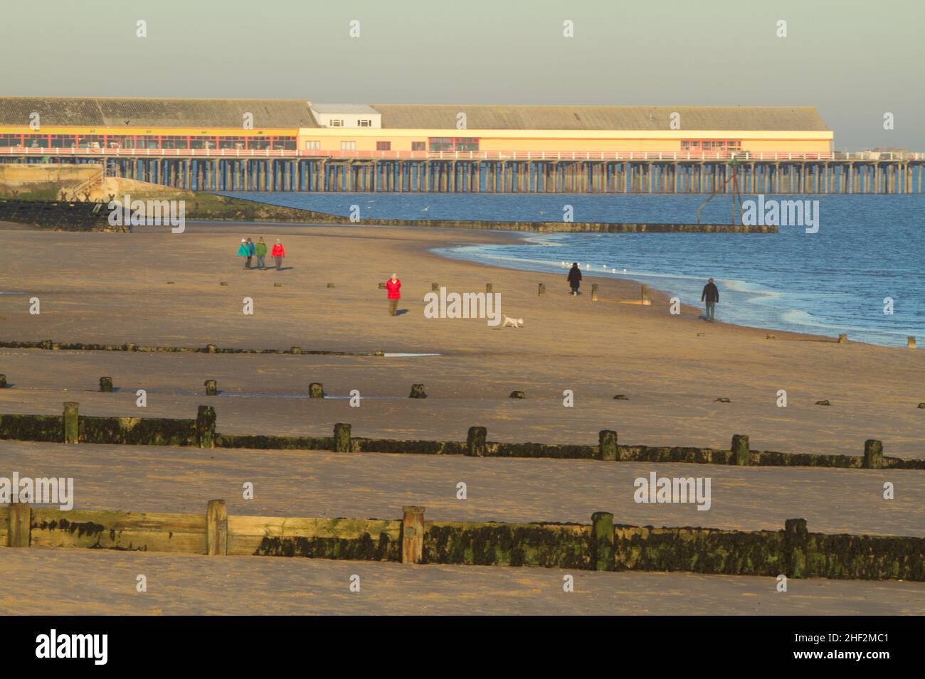 Walking on the beach at Frinton on Sea, Essex looking towards Walton pier Stock Photo