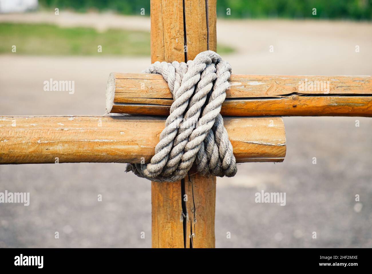 Closeup fragment of wooden fence. Wooden logs tied with strong rope