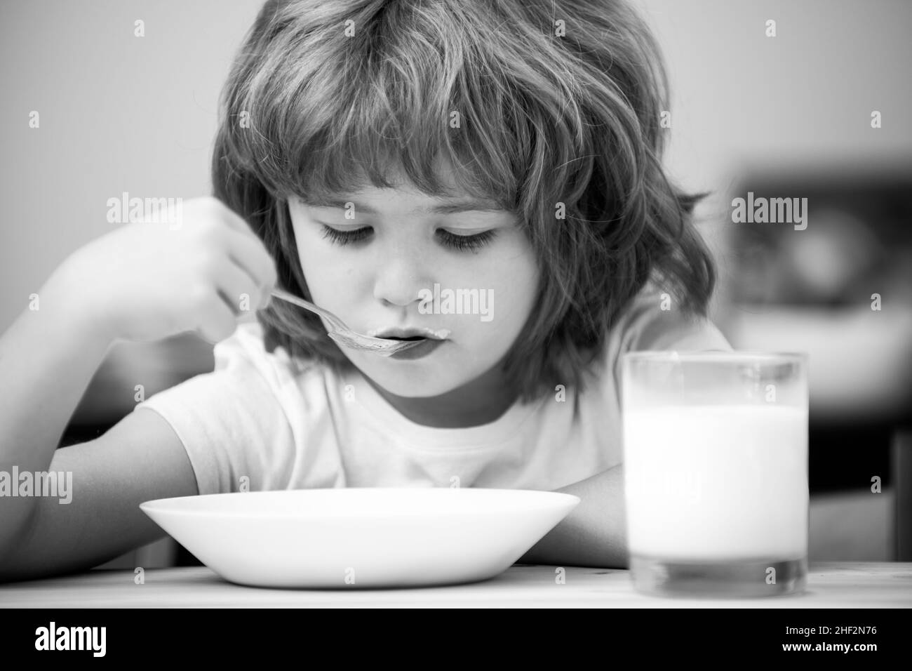 Caucasian toddler child boy eating healthy soup in the kitchen. Stock Photo