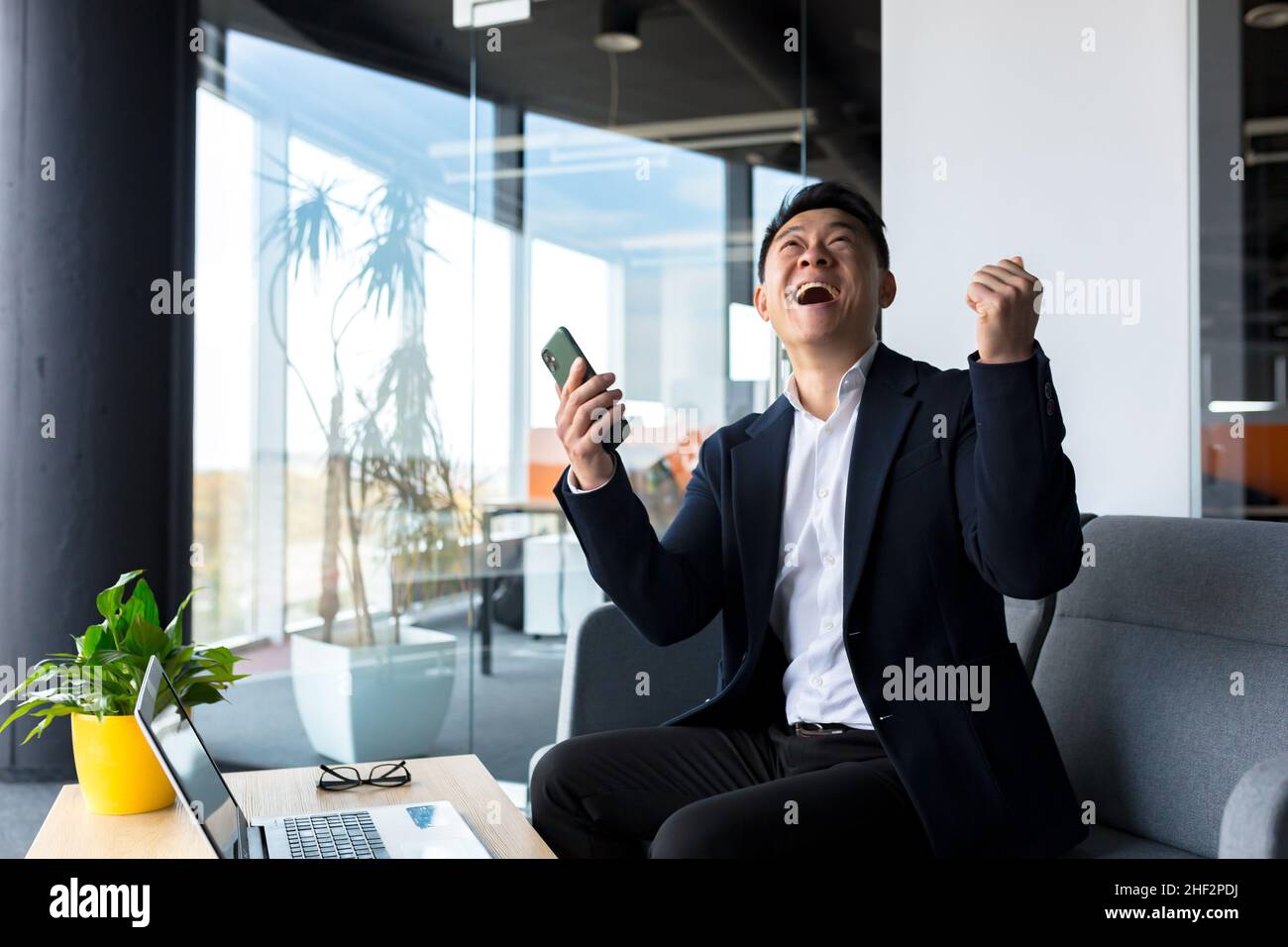 Successful business man, rejoices in victory and successful sales contract, smiles looks at camera in modern office, boss SEO celebrates winning Stock Photo