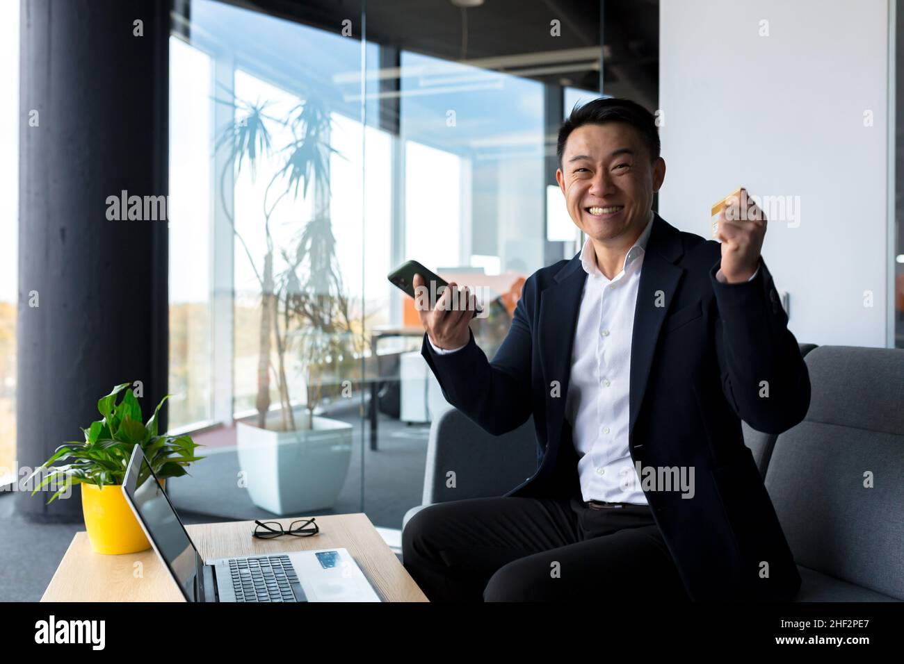 Successful business man, rejoices in victory and successful sales contract, smiles looks at camera in modern office, boss SEO celebrates winning Stock Photo