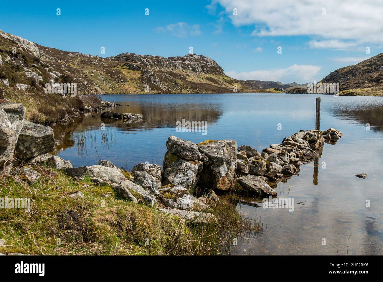 Ruined wall juts out into the still waters of Loch Dubh in Summer, Cromore, Isle of Lewis, Scotland, UK Stock Photo