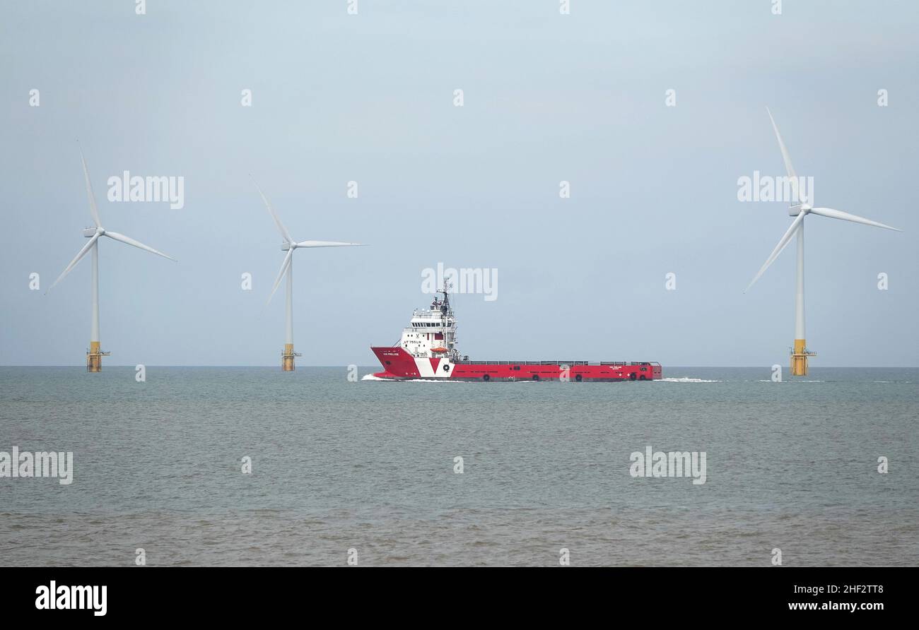 Offshore supply ship Vos Prelude sailing across a wind farm in the North Sea off the coast of Norfolk, England Stock Photo