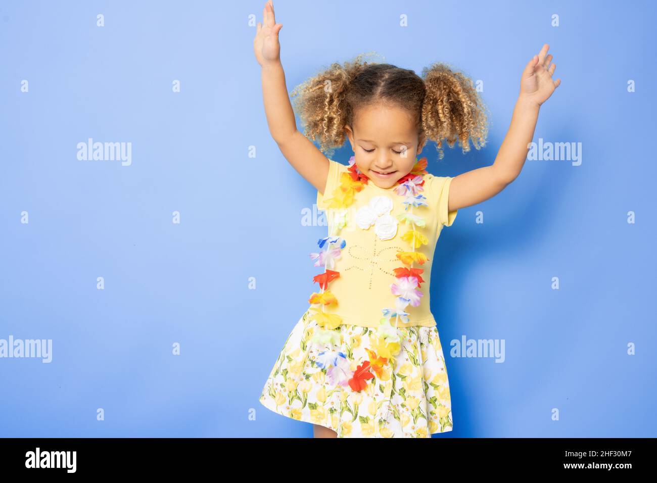 Full length photo of excited charming cute little girl with Happy little girl wearing Hawaiian necklace standing isolated over purple background. Stock Photo