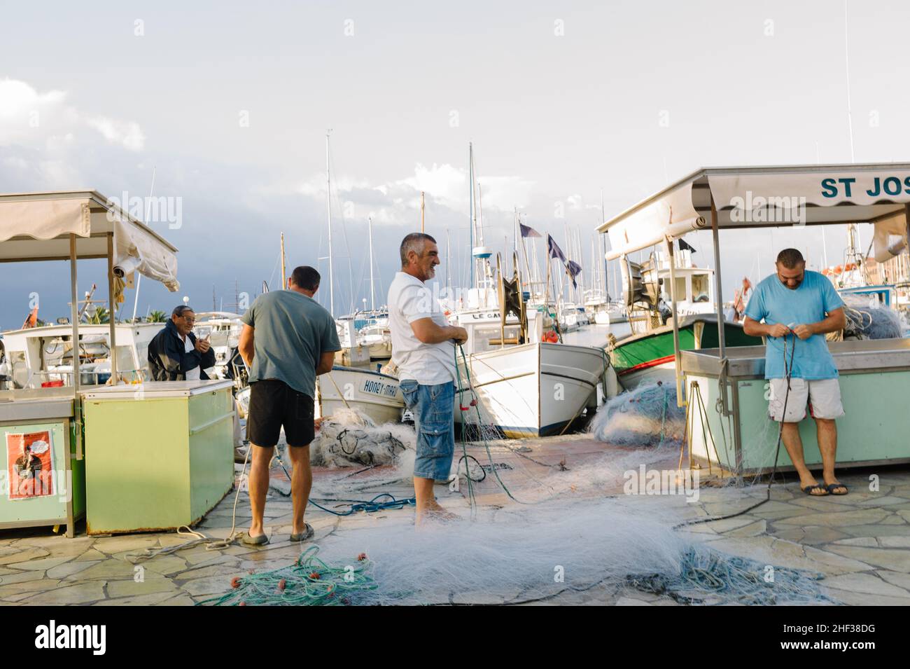 Fisherman mending their nets after a fishing trip at first light in the small French fishing port of Sanary sur Mer, Cote d' Azur in the south of France. 2014. Stock Photo