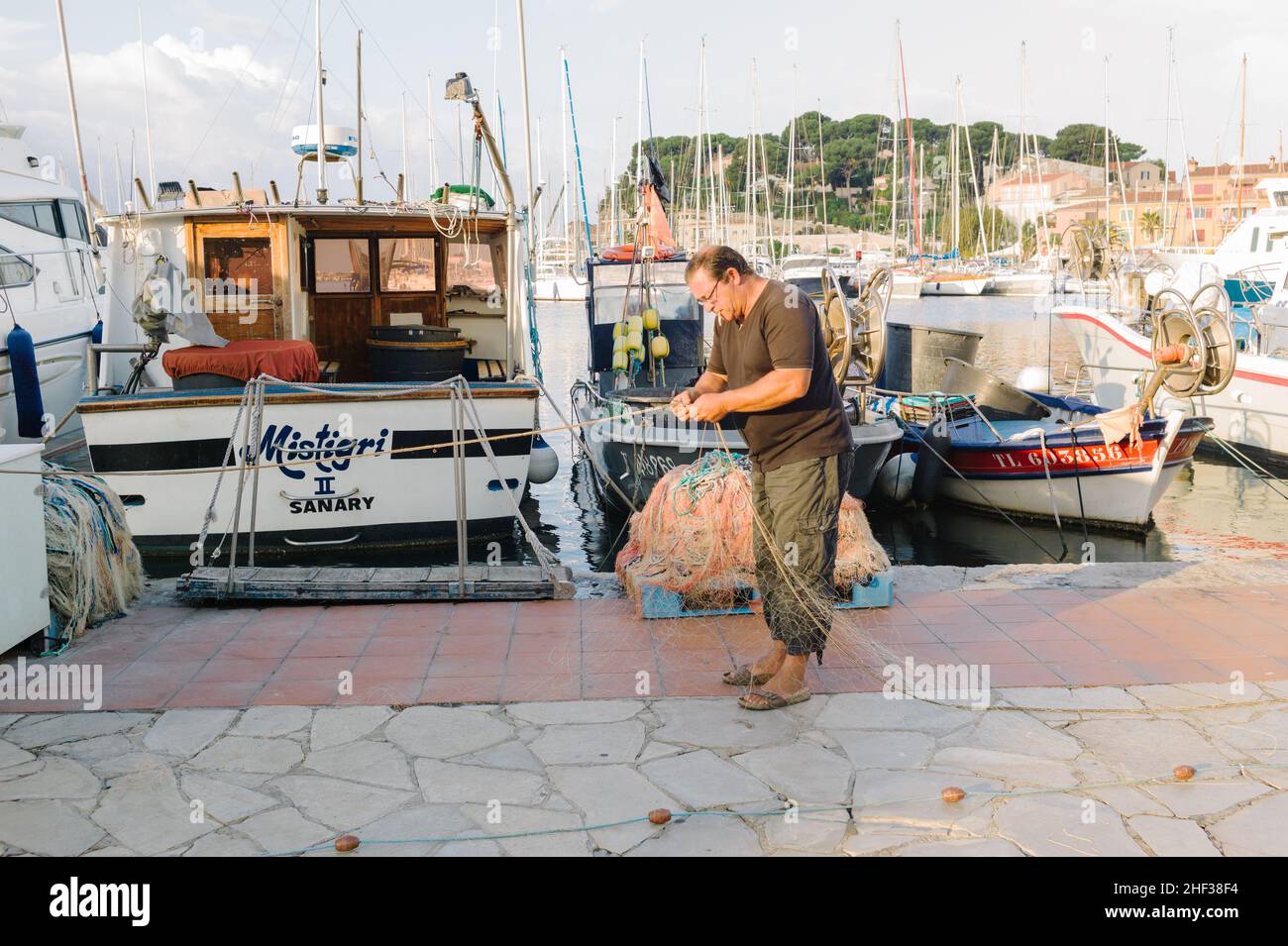 Fisherman mending his nets while smoking a cigarette after a fishing trip at first light in the small French fishing port of Sanary sur Mer, Cote d' Azur in the south of France. 2014. Stock Photo