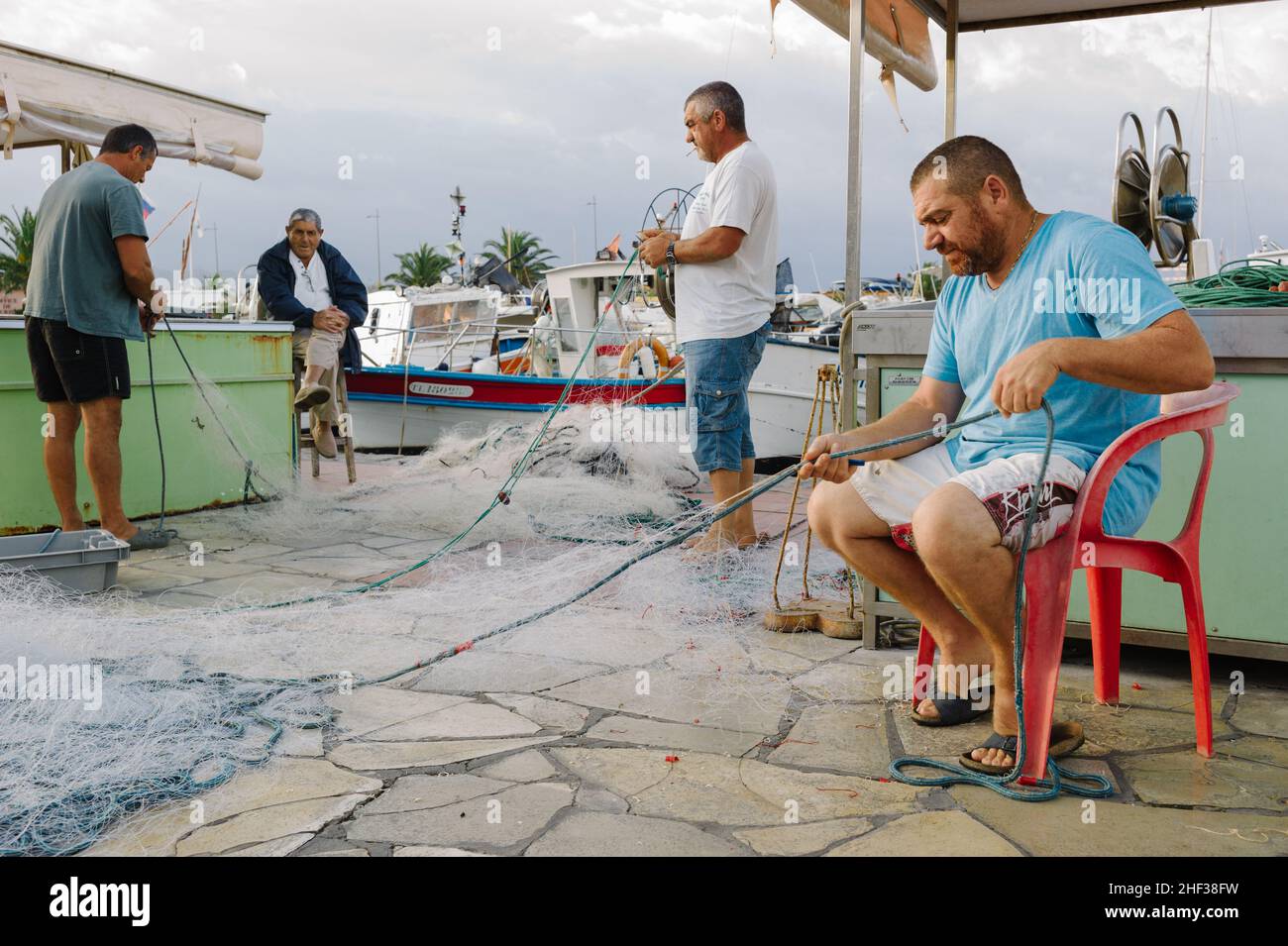 Fisherman mending their nets after a fishing trip at first light in the small French fishing port of Sanary sur Mer, Cote d' Azur in the south of France. 2014. Stock Photo