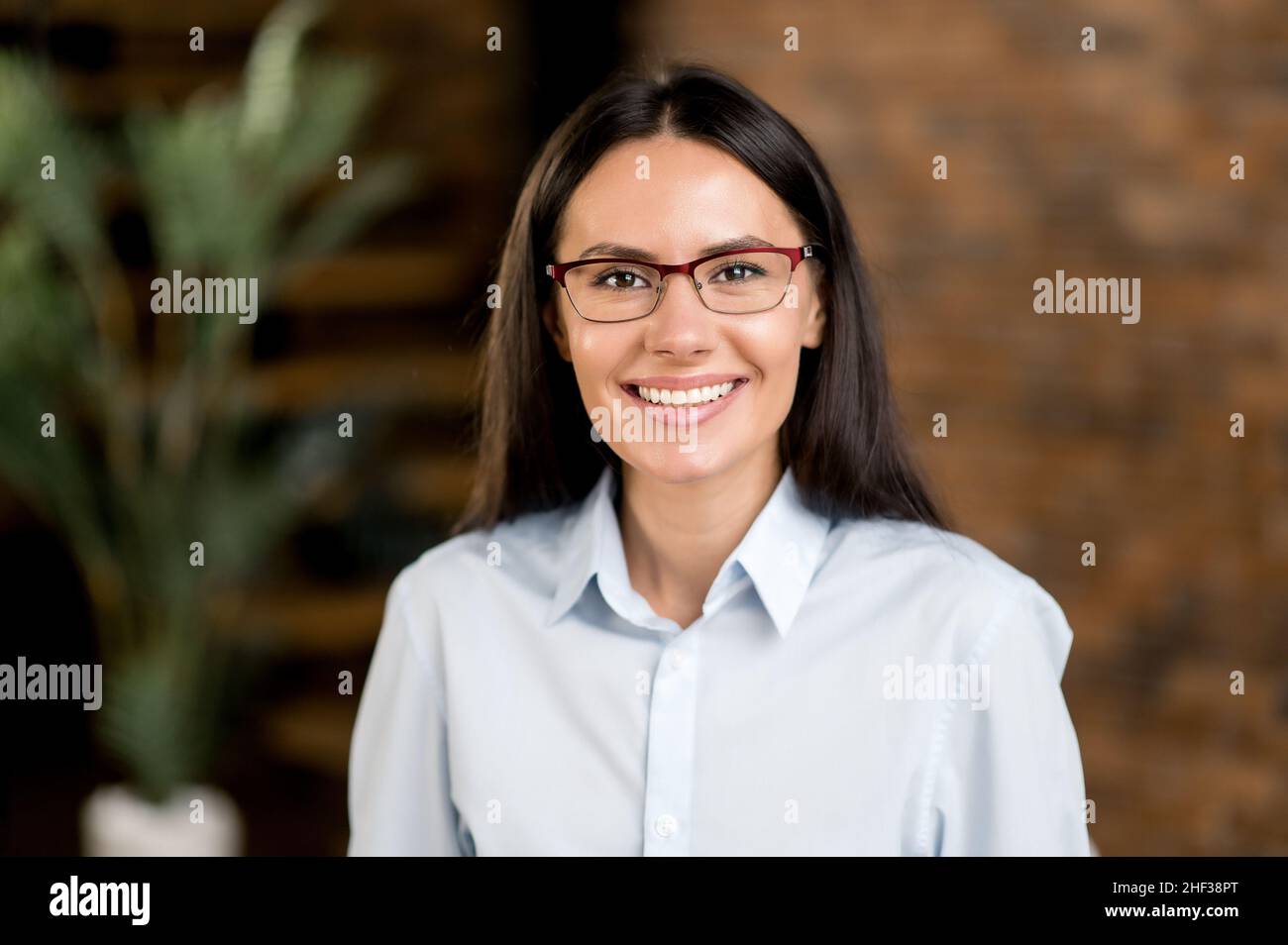 Close up portrait happy pleasant caucasian brunette business woman, company executive or manager wearing glasses, in formal clothes, looking at the camera, smiling friendly Stock Photo