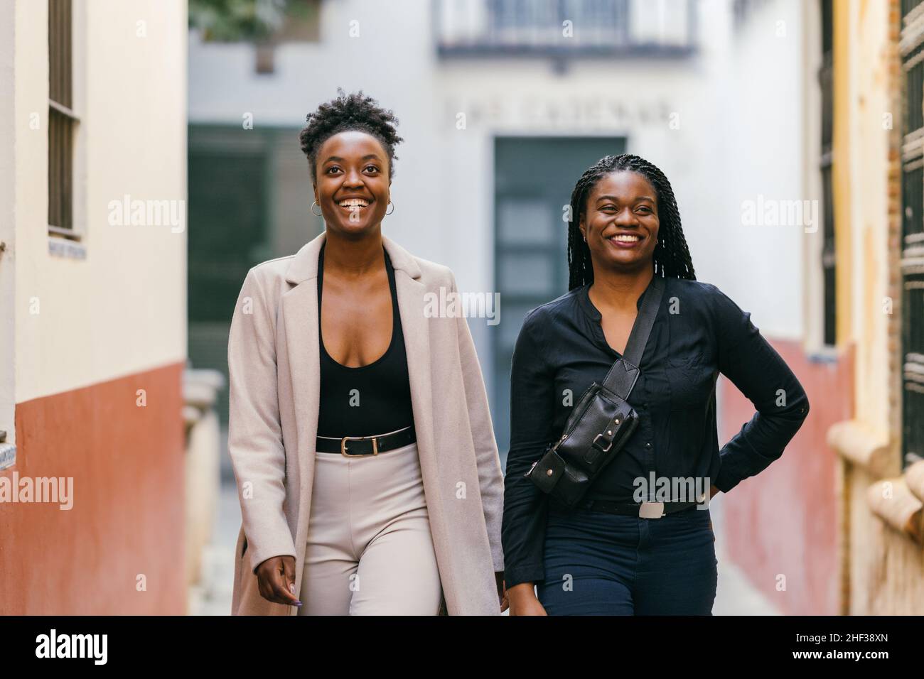 Two smiling african models walking through a narrow street Stock Photo
