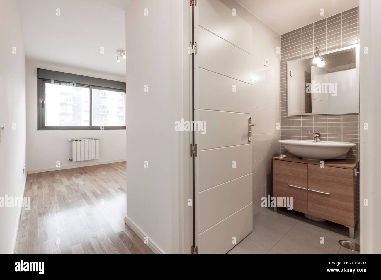 Empty bedroom with large window and en suite bathroom with parquet floors Stock Photo