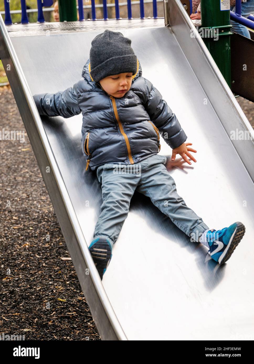 Two year old boy on city playground sliding board Stock Photo
