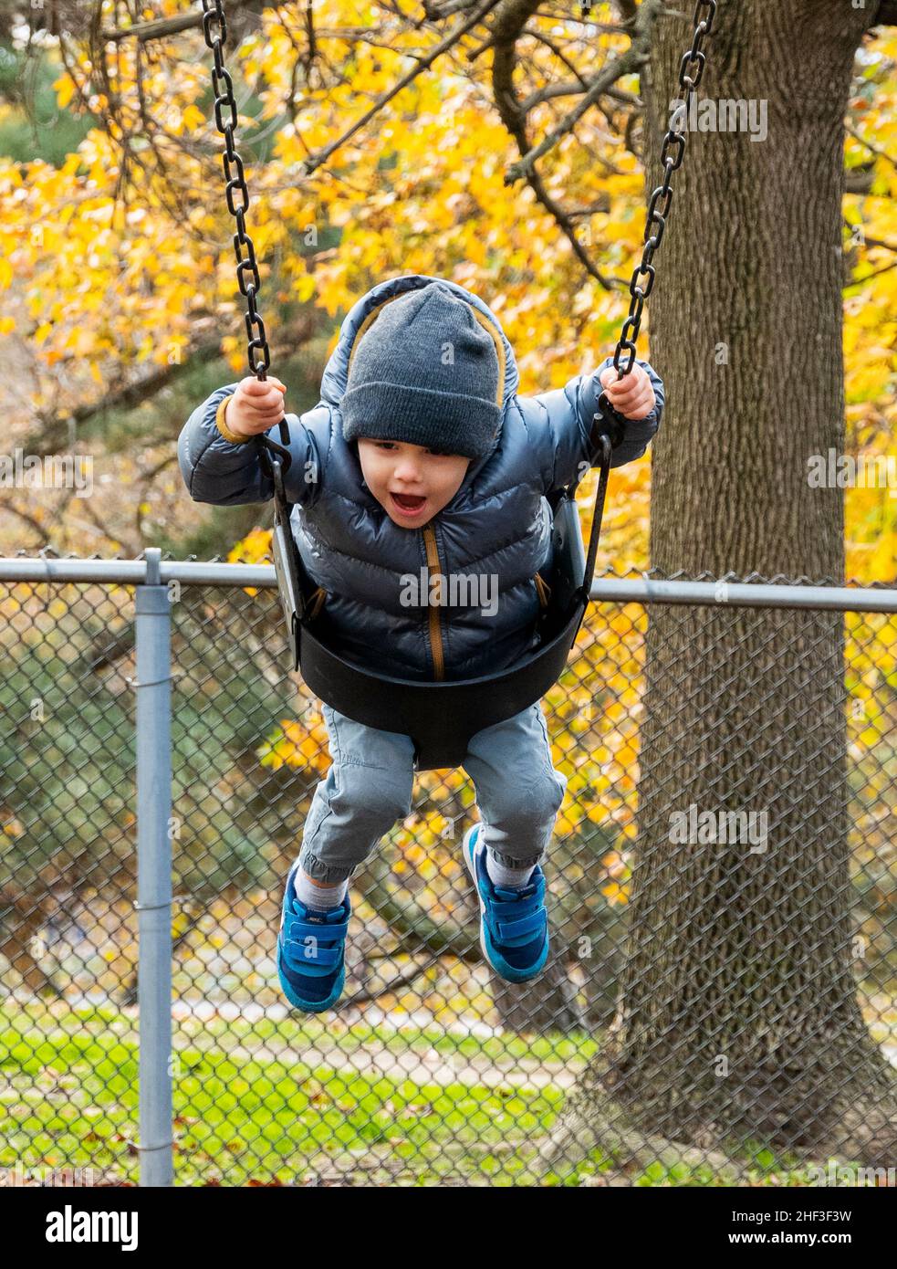 Two year old boy swinging on city park swing set; Corinthian Gardens; Philadelphia; Pennsylvania; USA Stock Photo
