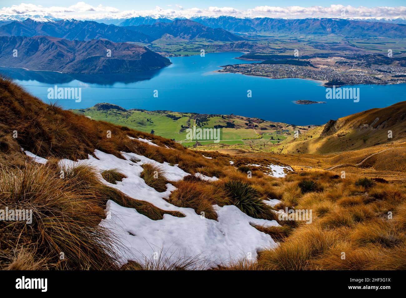 What a view from above the snow line on Roys Peak looking down to Lake Wanaka and the town of Wanaka Stock Photo
