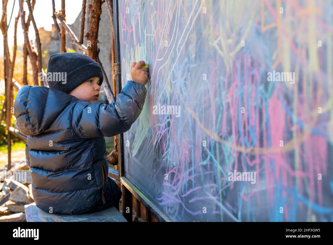 Two year old boy drawing with colorful chalk on city park chalk board Stock Photo Alamy