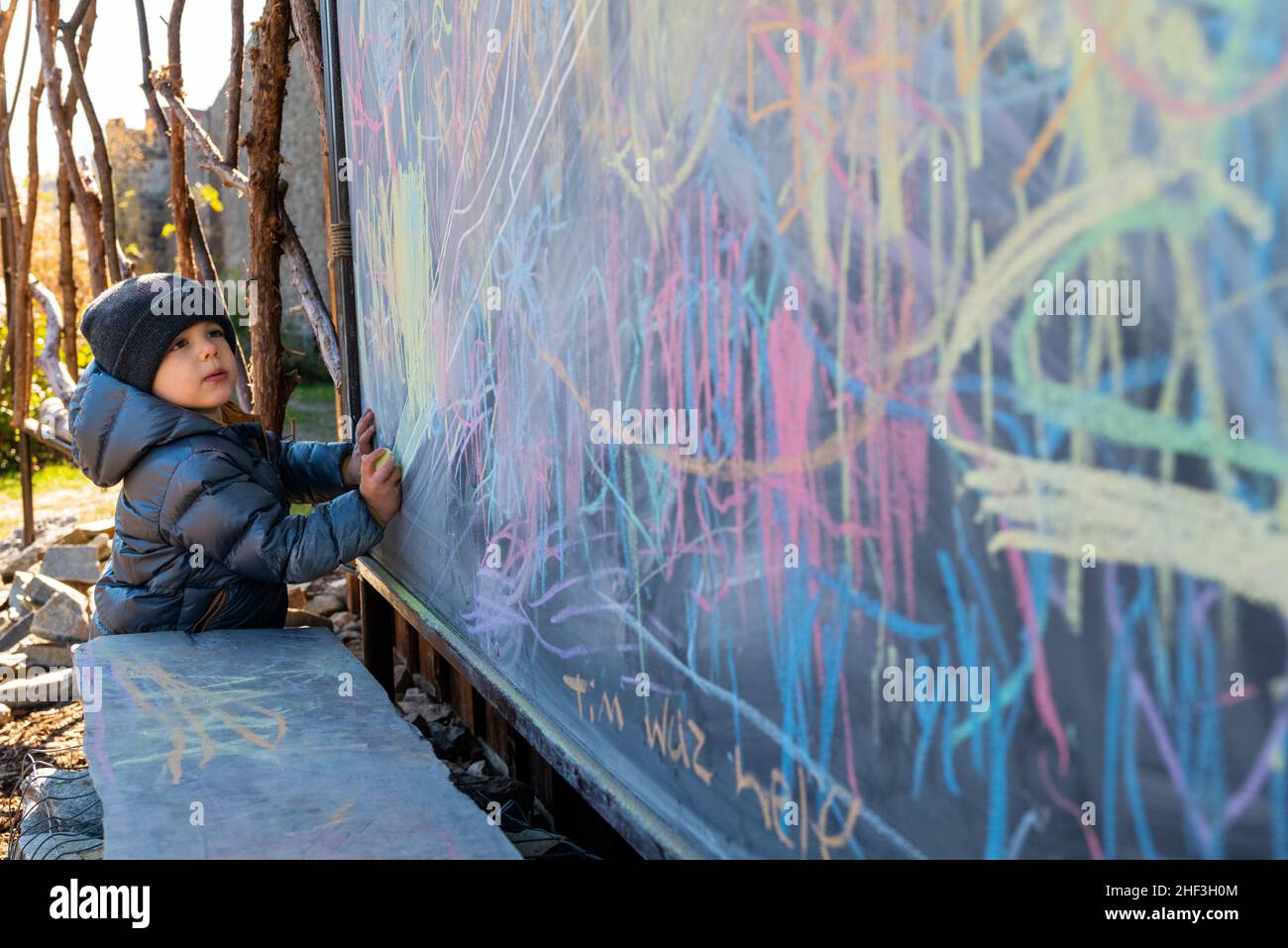 Two year old boy drawing with colorful chalk on city park chalk board Stock Photo Alamy