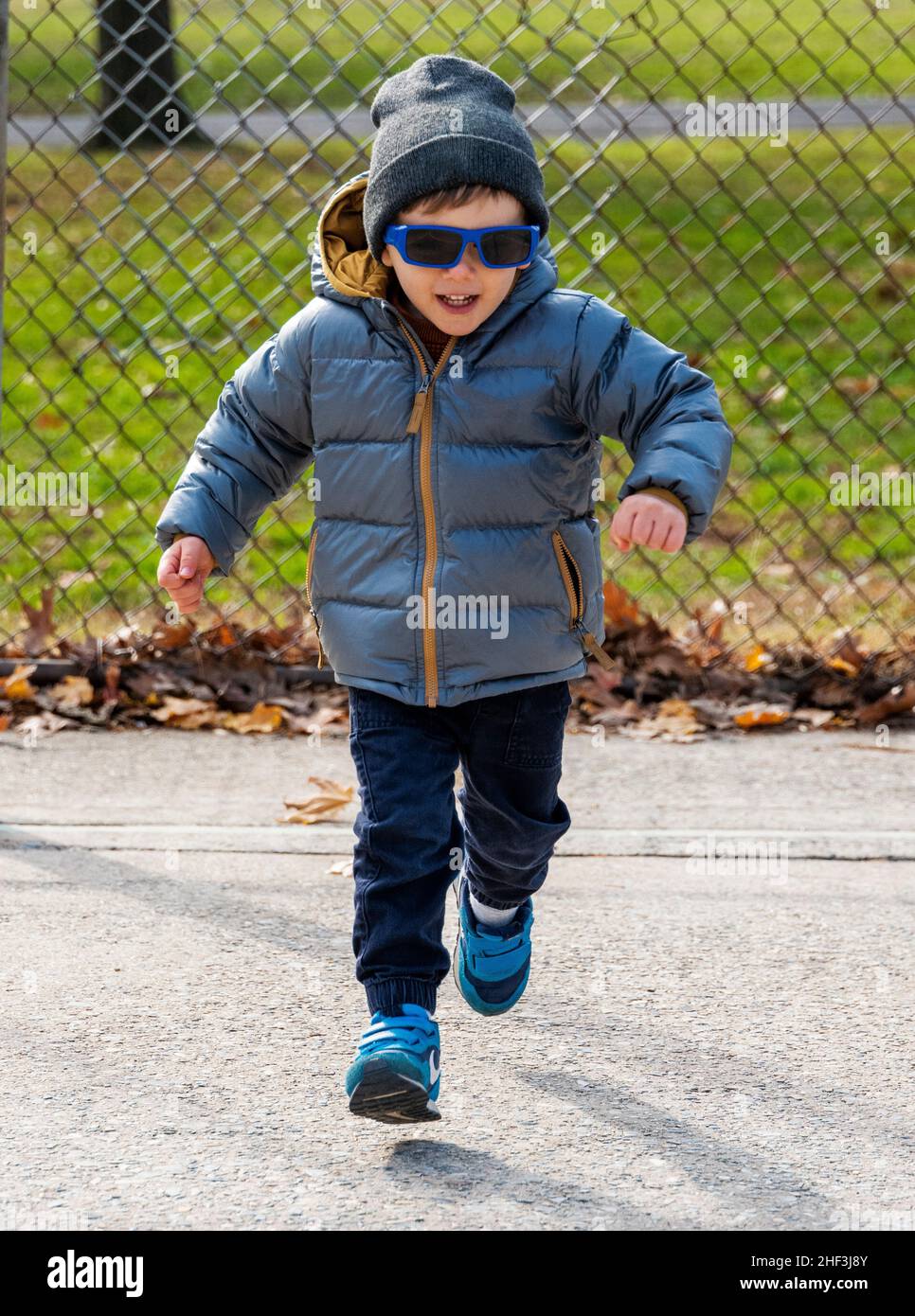 Two year old boy with sunglasses running on city park playground; Corinthian Gardens; Philadelphia; Pennsylvania; USA Stock Photo