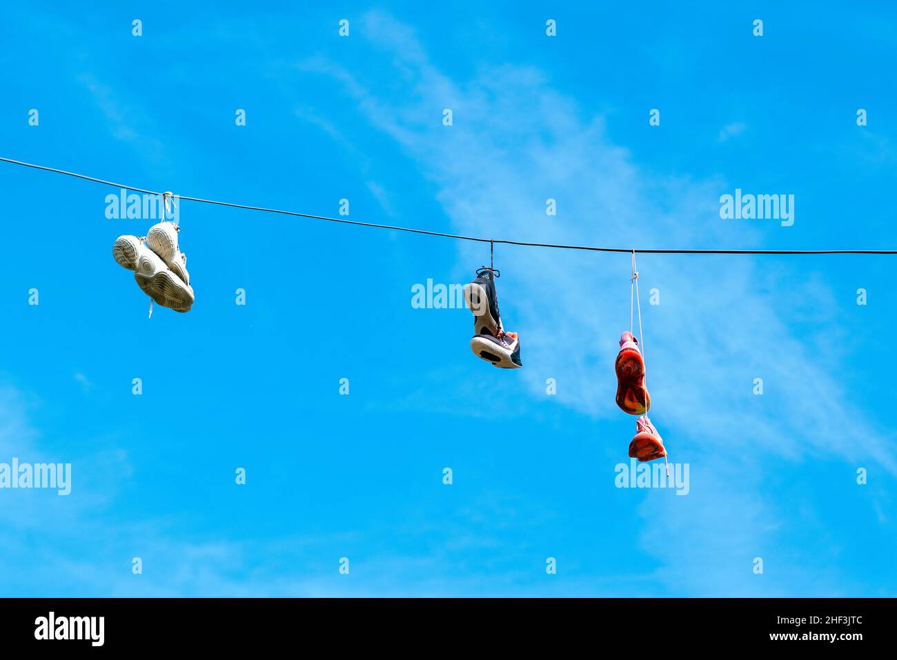 Sneakers hanging by shoe laces on power line Stock Photo