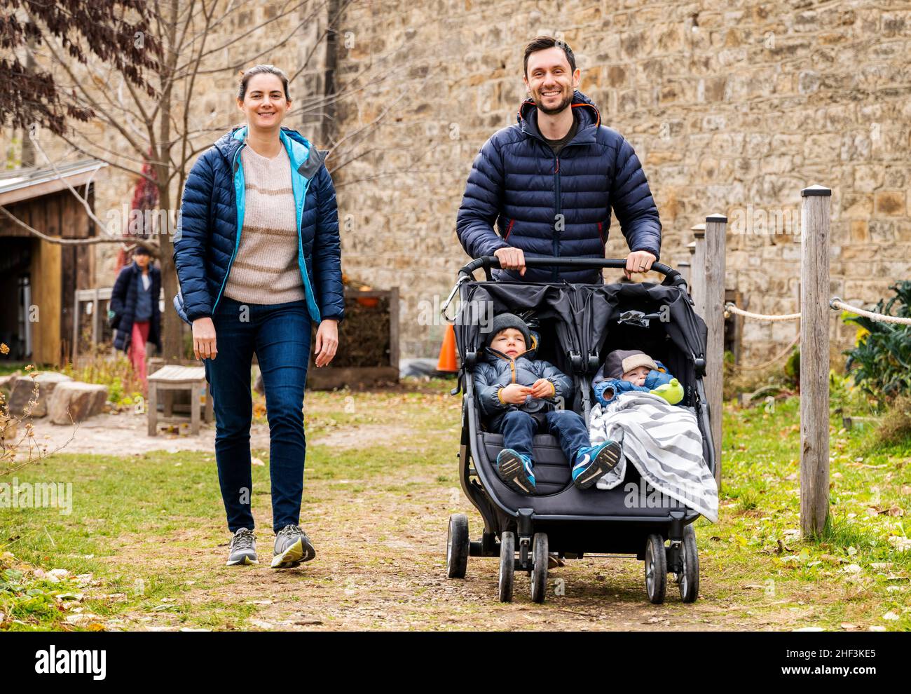 Outdoor photo of parents pushing stroller with 2 1/2 year old & 7 month old brothers; Corintian Gardens; Philadelphia; Pennsylvania; USA Stock Photo