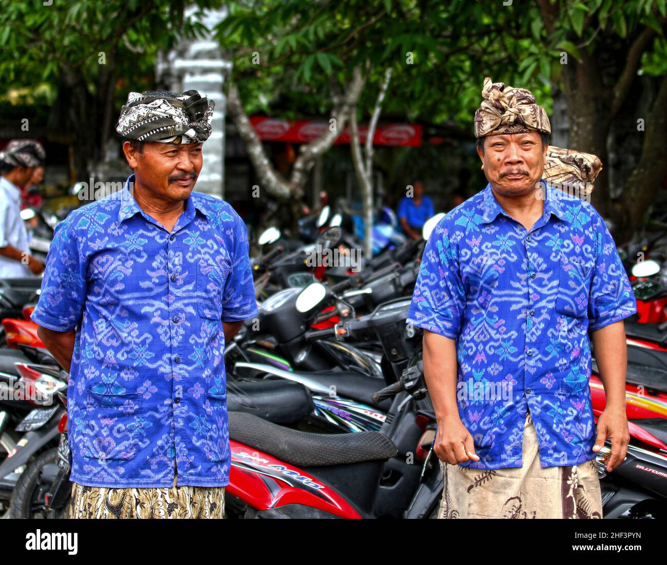 Village seniors dressed in blue batik shirts and batik udeng headwear at a ceremony taking place in the village of Ketewel in Gianyar, Bali, Indonesia Stock Photo
