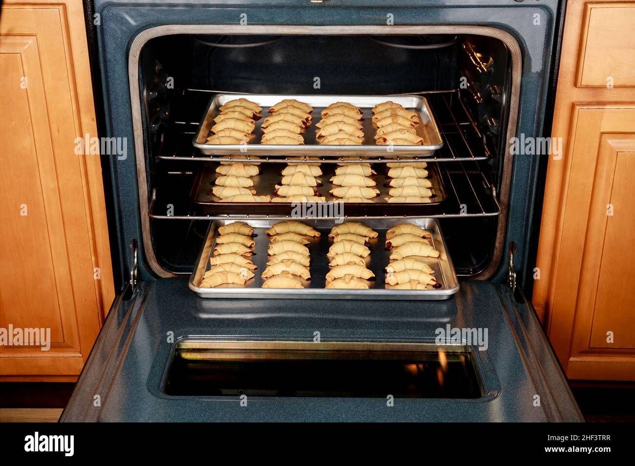 Electric oven with baking pans with baked crescent cookies Stock Photo