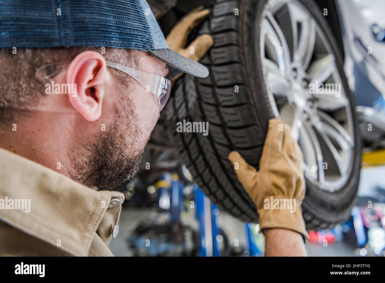 Caucasian Professional Authorized Dealership Auto Service Worker Replacing Tires and Balancing