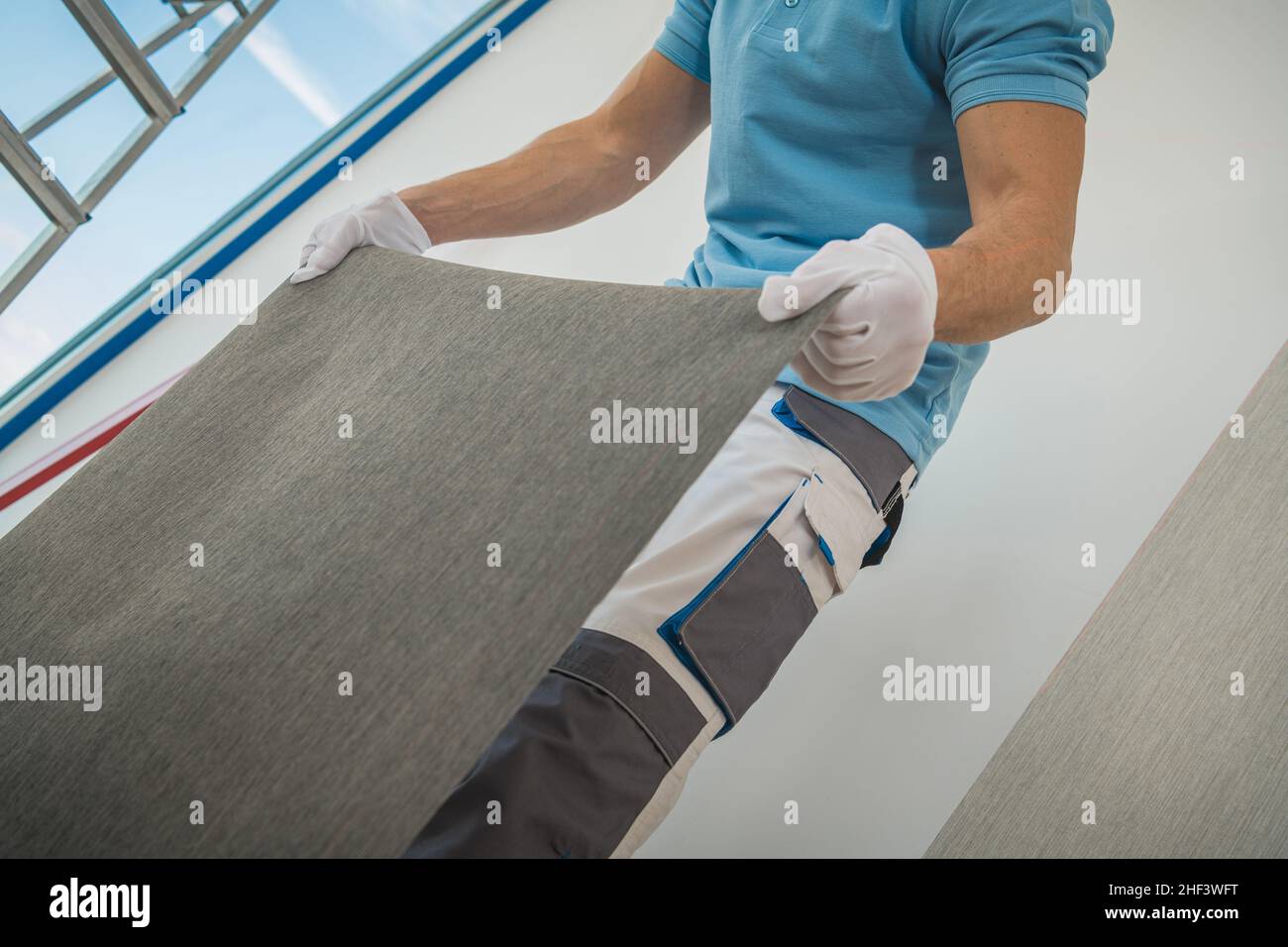 Worker Preparing Piece of Wall Vinyl Wallpaper to Apply to His Clients Apartment Wall Stock