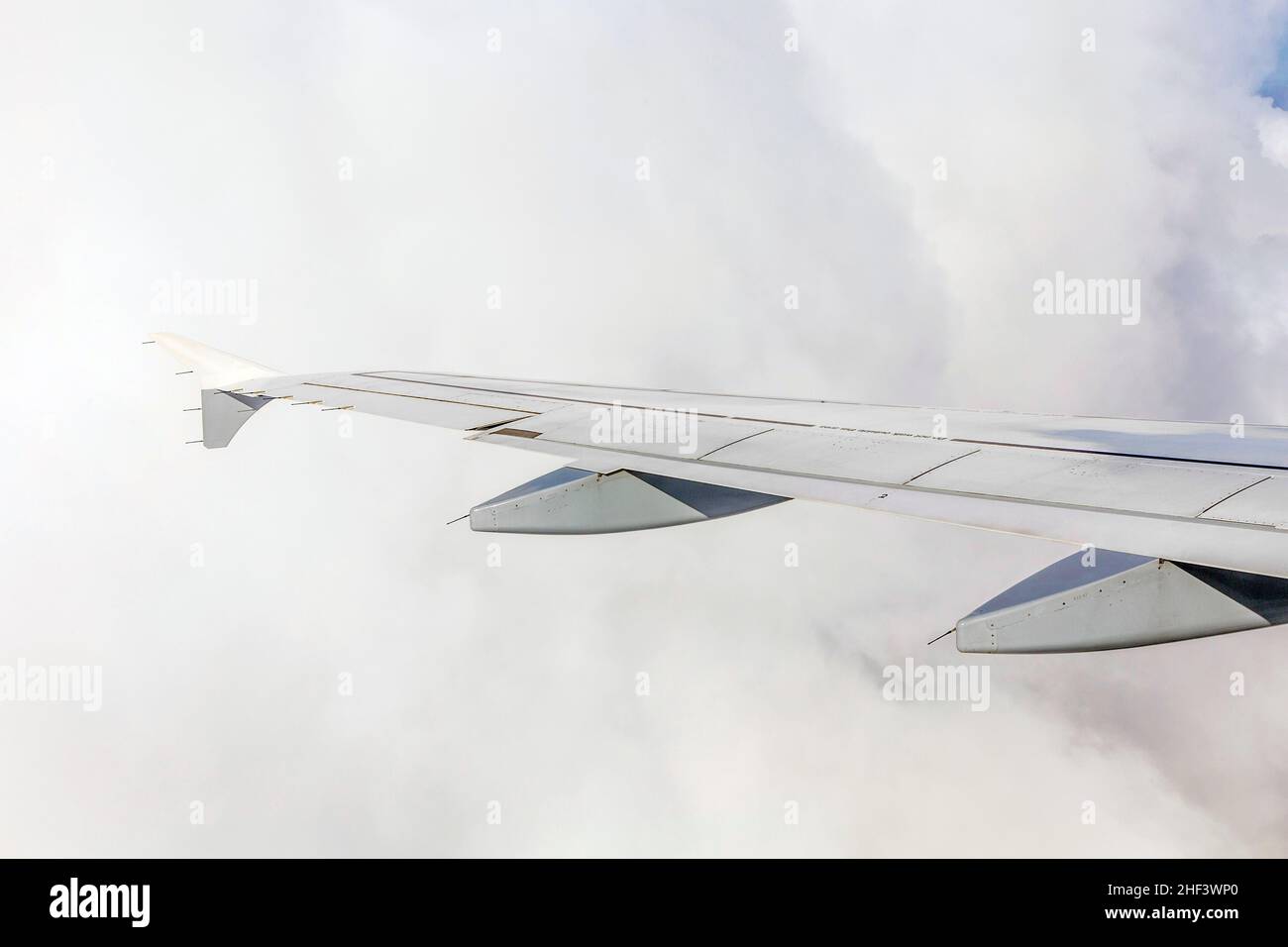 Wing of an airplane flying above the clouds Stock Photo - Alamy