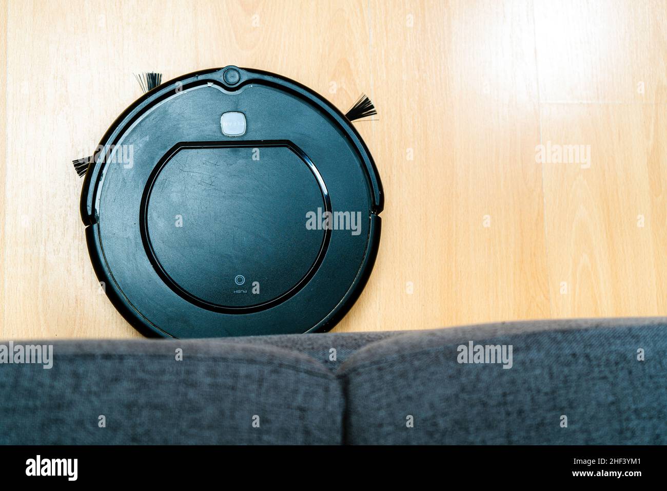 A Robot vacuum cleaner cleaning under the sofa Stock Photo Alamy