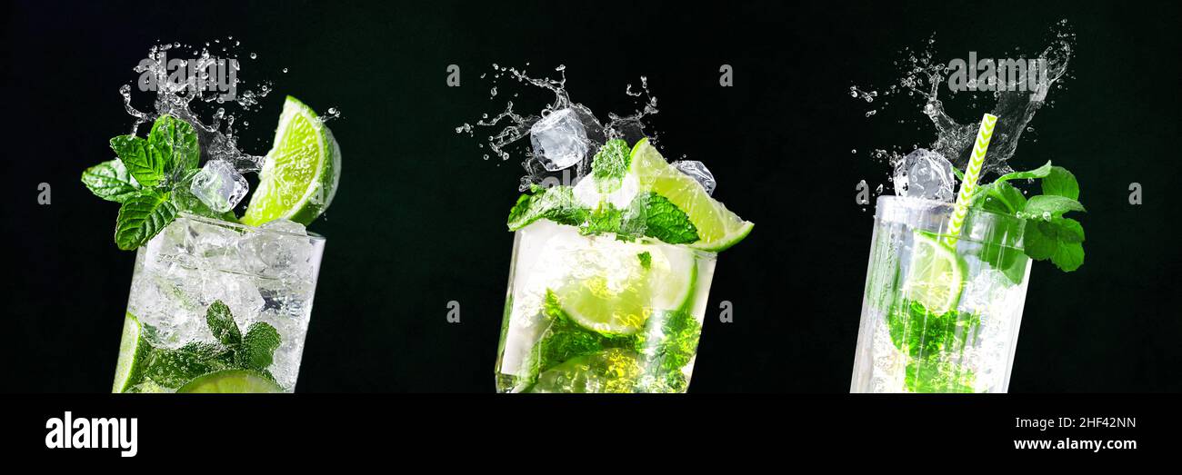 Glasses of Mojito with splashes and flying ice cubes on black and green background in bar | Limes, water, drops Stock Photo