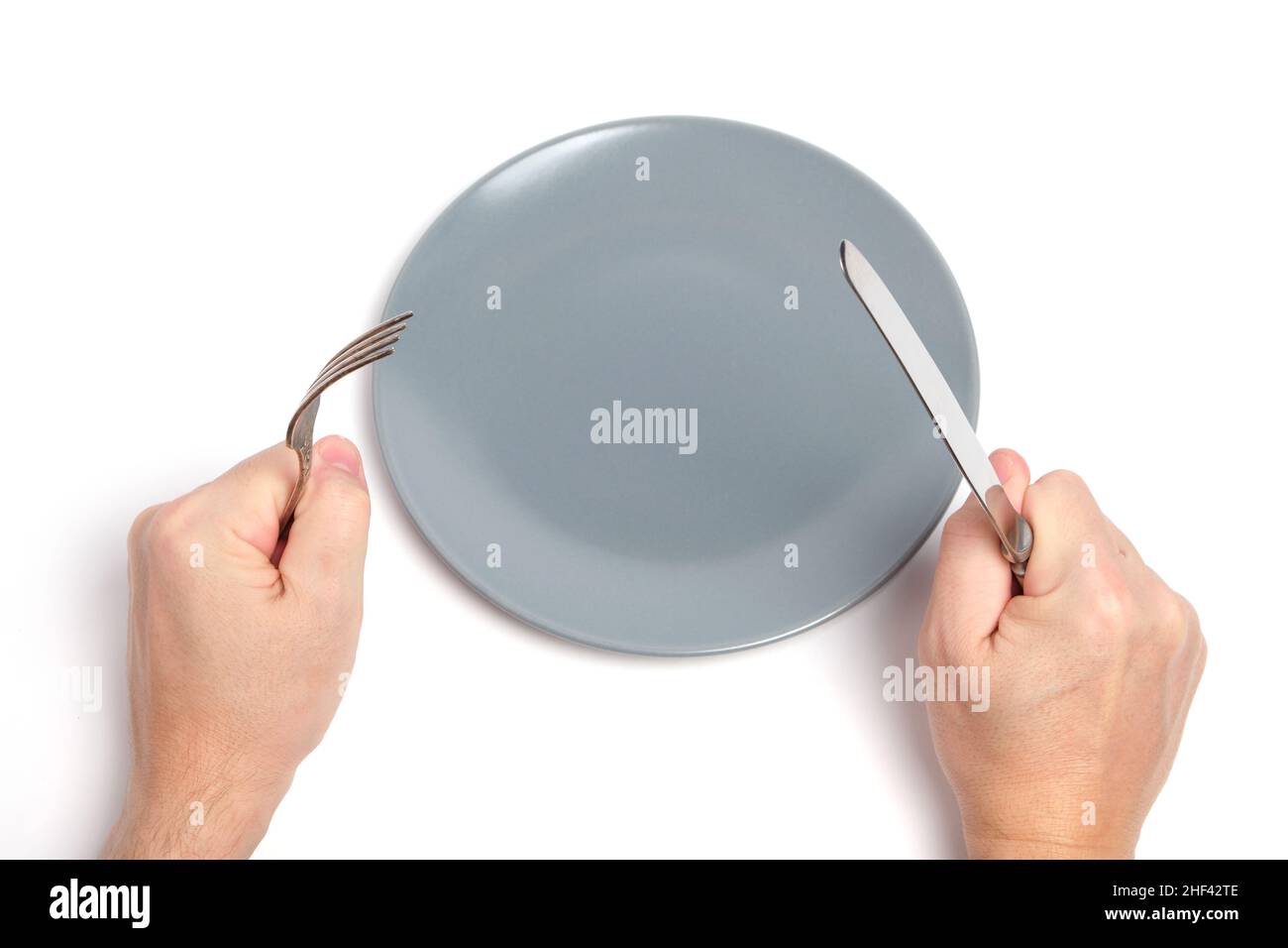 Empty plate and hands with cutlery spoon and fork white background Stock Photo
