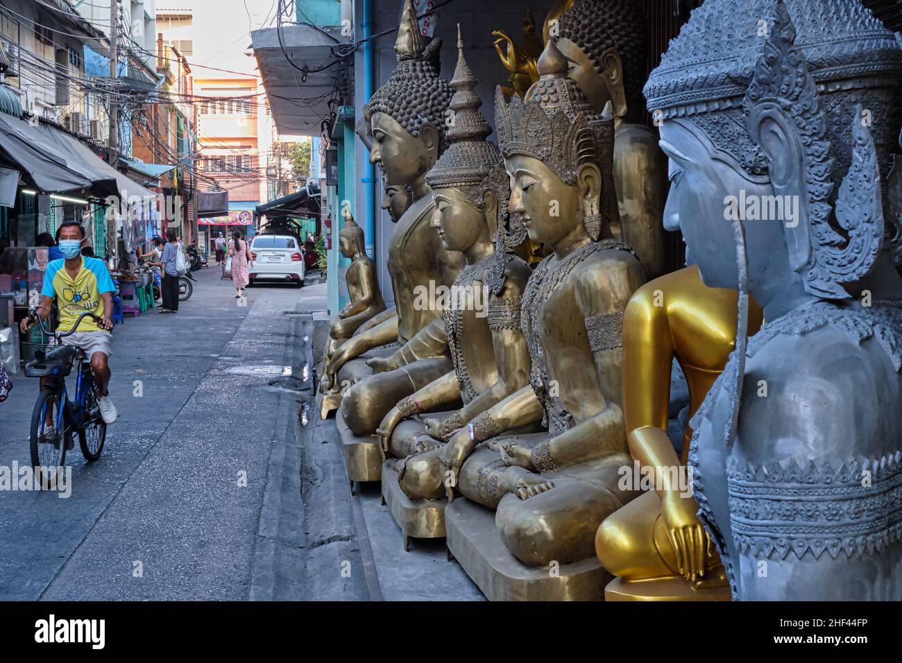 A row of different Buddha statues is placed outside a shop for Buddhist