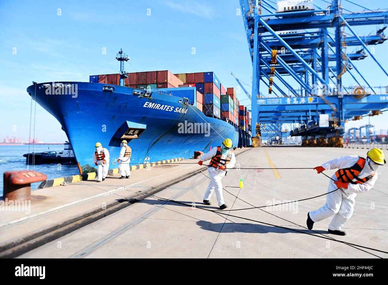 QINGDAO, CHINA - JANUARY 14, 2022 - Dockers attach cables to cargo vessels at the fully automated Qianwan Port in Qingdao, East China's Shandong Provi Stock Photo