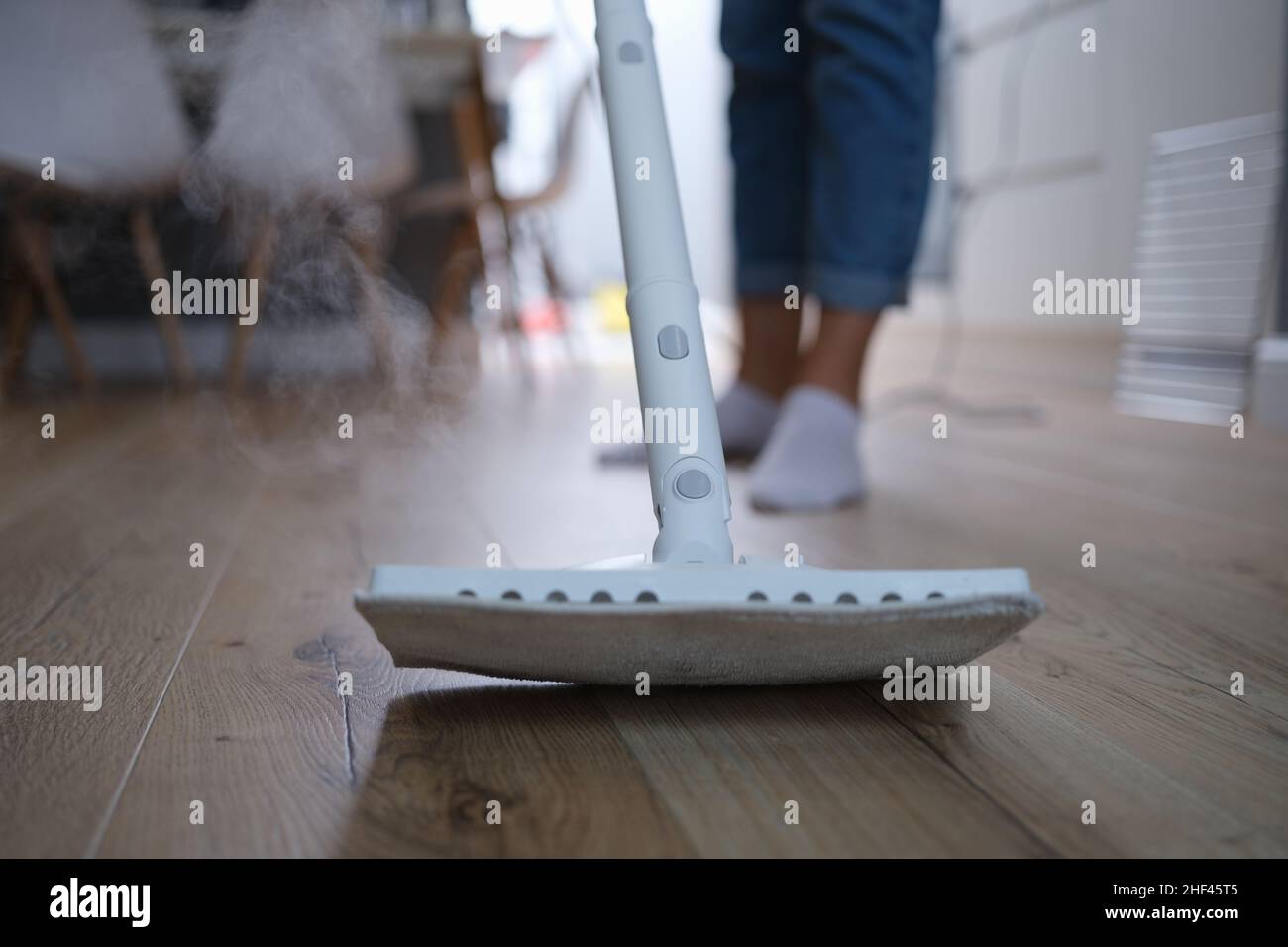 A steam mop washes the parquet on the floor of the house Stock Photo
