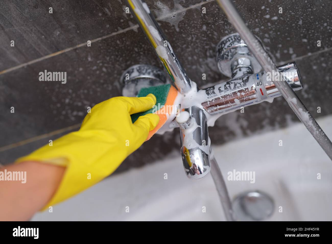 A hand in a yellow glove washes the mixer in the bathroom Stock Photo ...