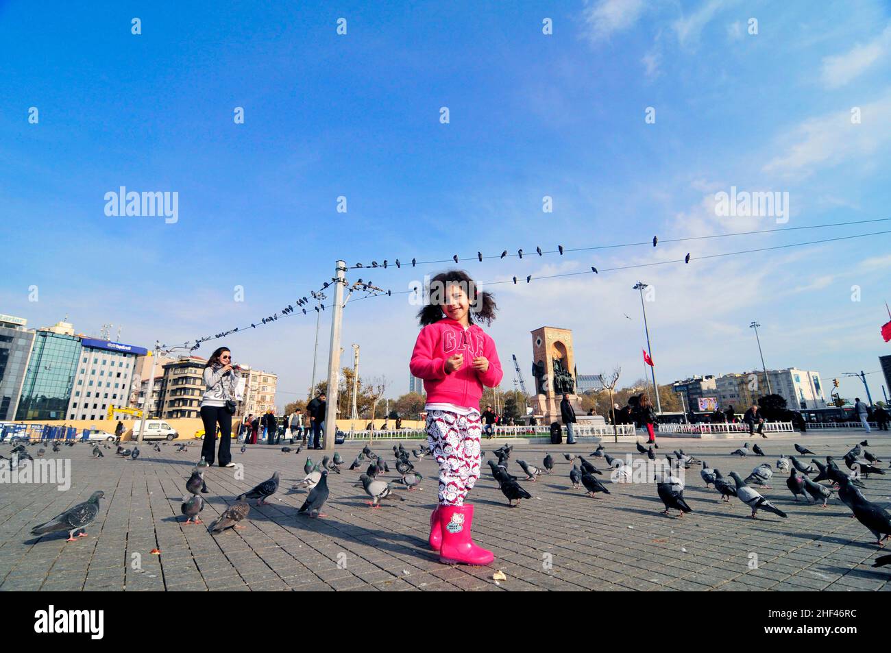 A Turkish girl running and playing between the pigeons in Taksim square in Istanbul, Turkey. Stock Photo