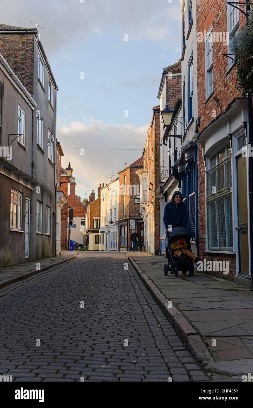 man pushing a buggy down Wormgate, an old cobbled street at the back of the  stump church. Stock Photo