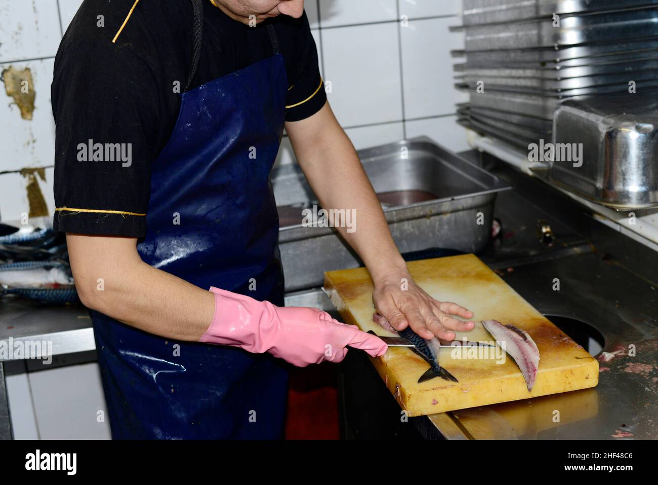 A young Turkish cook slicing Mackerel fish filets for the popular fish sandwiches in Istanbul, Turkey. Stock Photo