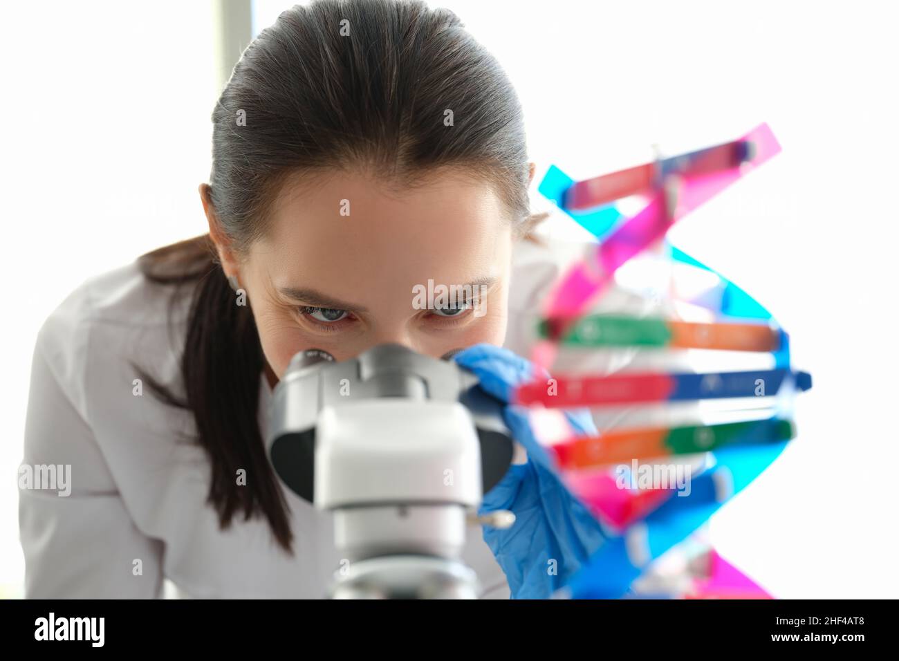 A woman biologist looks through a microscope, eyes close-up Stock Photo