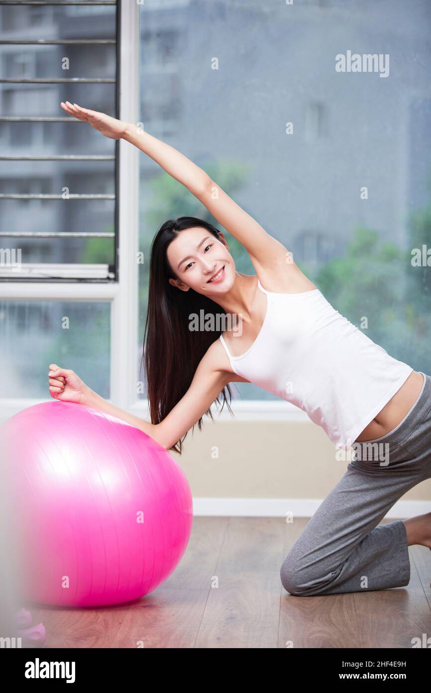 Young woman doing yoga at home with a fitness ball Stock Photo