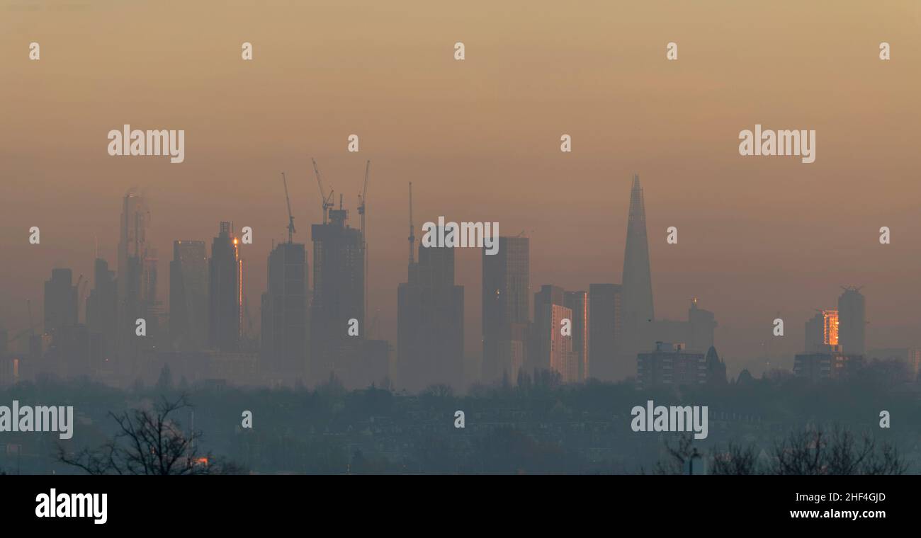 Wimbledon, London, UK. 14 January 2022. Dawn sunlight strikes the edge of St George Wharf Tower, left, at Vauxhall through morning mist on a day that high air pollution level warning goes out. Credit: Malcolm Park/Alamy Live News Stock Photo