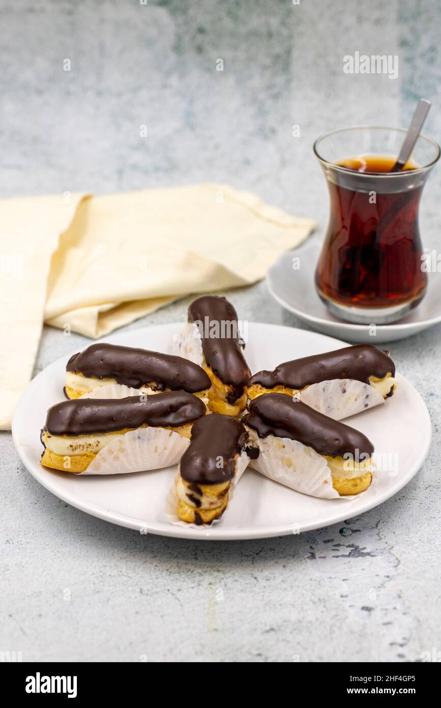 Tasty eclairs and cup of tea on stone table. Traditional french dessert ...