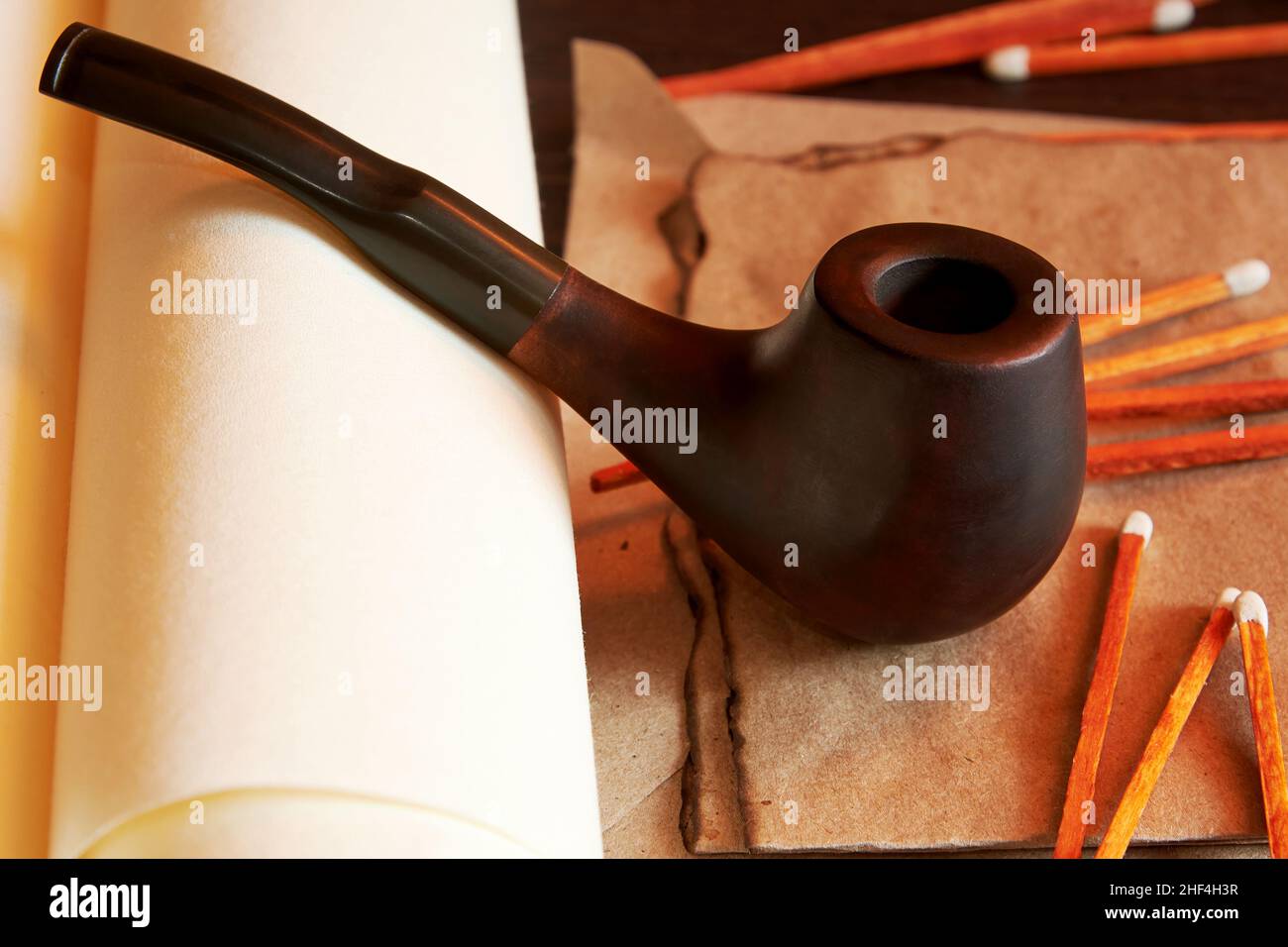 Smoking pipe with matches and burnt letter and old scrolls. Atmospheric