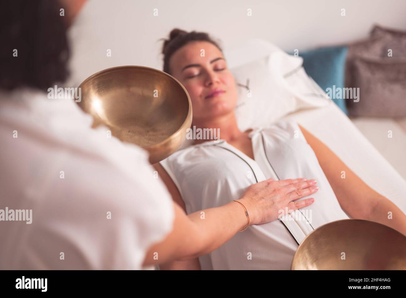 Female therapist with singing bowl practicing sound healing therapy on ...