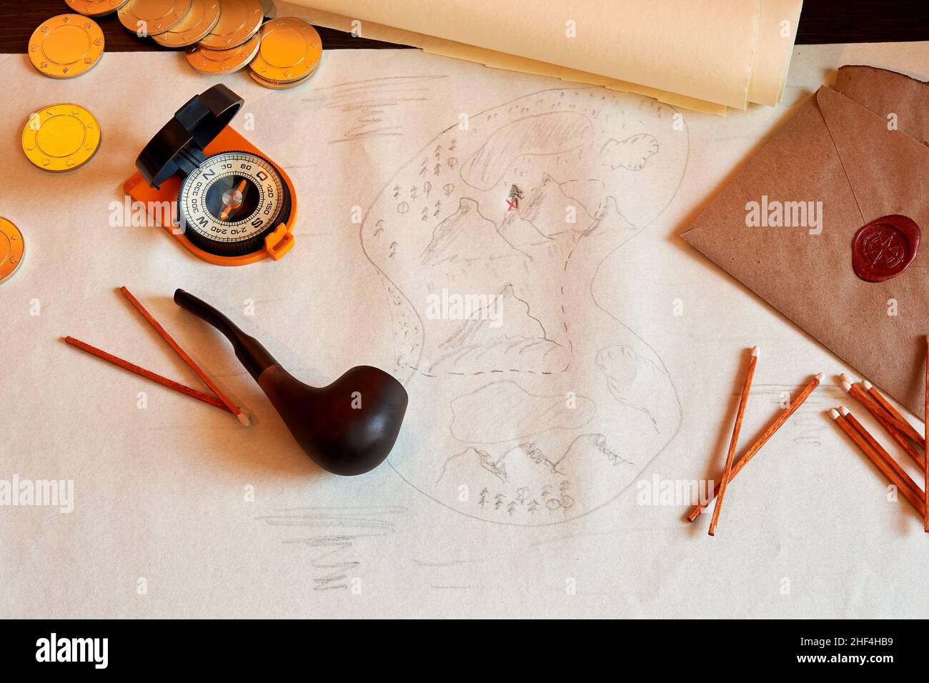 Table with an old treasure map, smoking accessories, compass, and coins. Games and adventures and exploring backgrounds Stock Photo