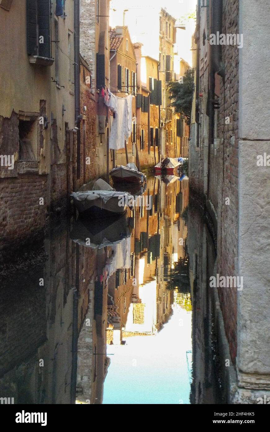 canal in Venice town with mooring boats and clothes hanging out the window Stock Photo