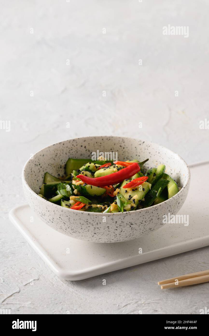 Asian spicy salad Broken Cucumbers with fresh coriander, ginger on white background. Popular Chinese cold appetizer. Close up. Vertical format. Copy s Stock Photo