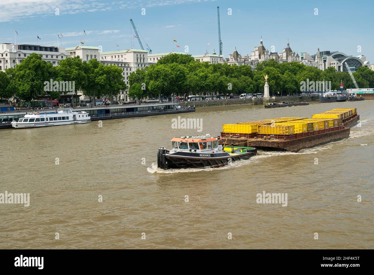 Cory tugboat Resource going up the river Thames pulling empty containers towards Westminster bridge with Statue of Golden Eagle of the RAF Memorial. Stock Photo