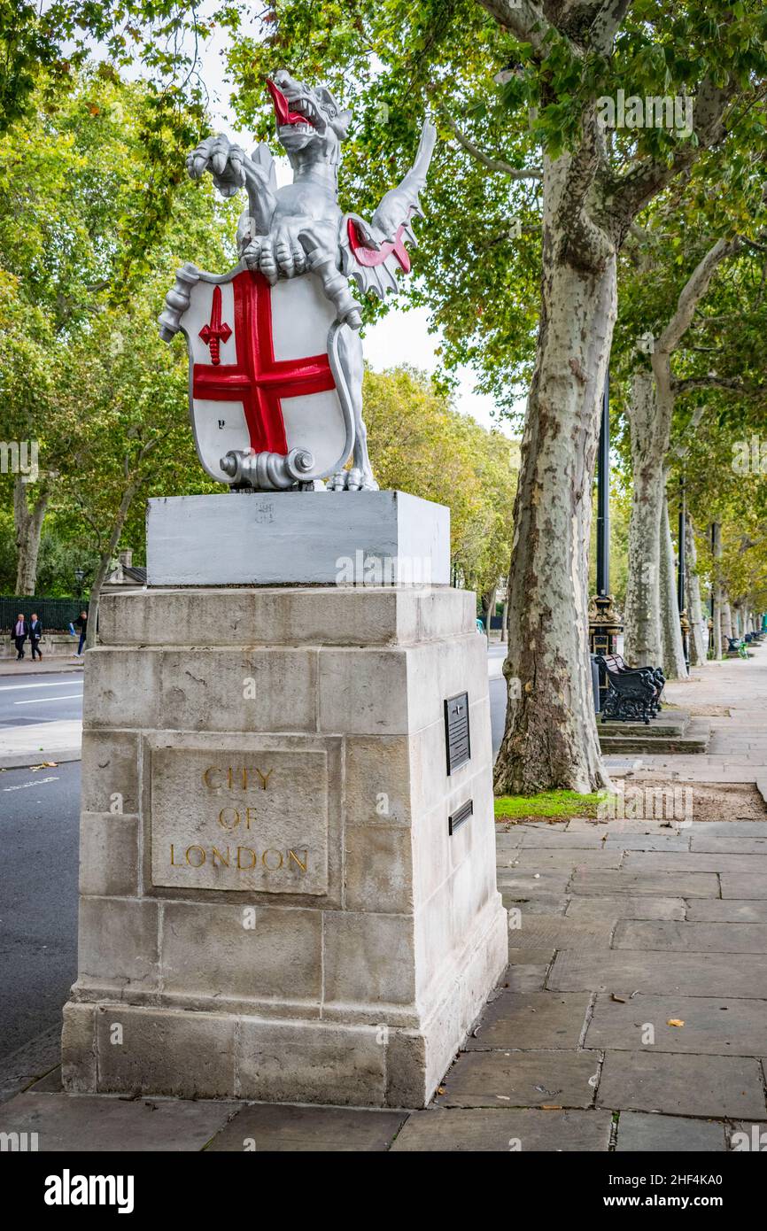 A dragon statue with St Georges cross shield marking boundary for the city of London along the embankment at river Thames under the treeline in London Stock Photo