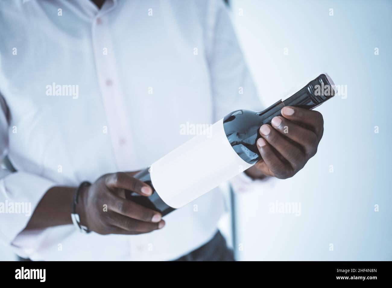 Strong Hands of a Businessman Hold a Black Bottle of Wine. Party Time. Close-up. High quality photo Stock Photo